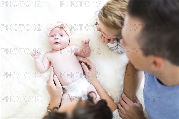 Parents lying on bed with son (4-5) and daughter (0-1 months)