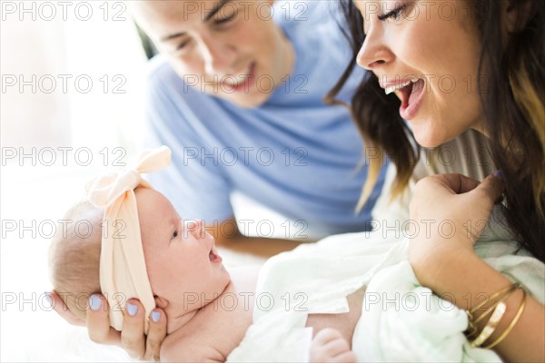 Parents lying on bed with  daughter (0-1 months)