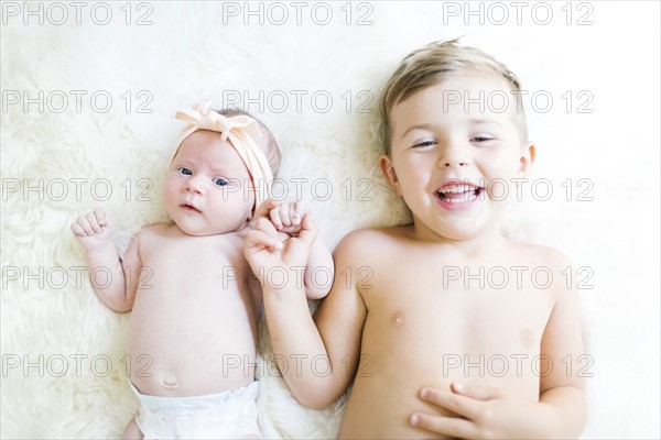 Brother (4-5) and sister (0-1 months) lying on bed