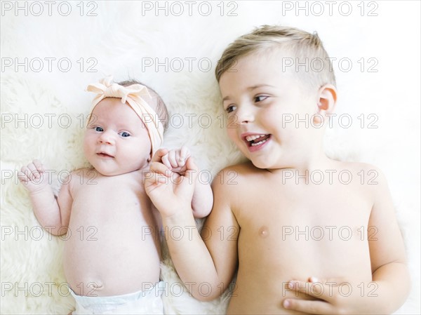 Brother (4-5) and sister (0-1 months) lying on bed