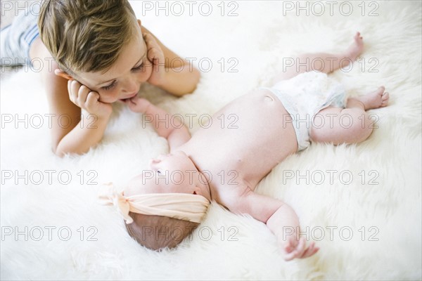 Brother (4-5) and sister (0-1 months) lying on bed