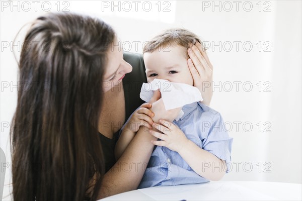 Young boy (4-5) blowing nose
