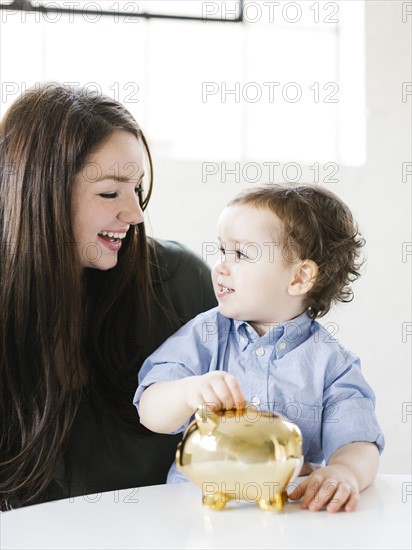 Mother teaching son (4-5) how to save money