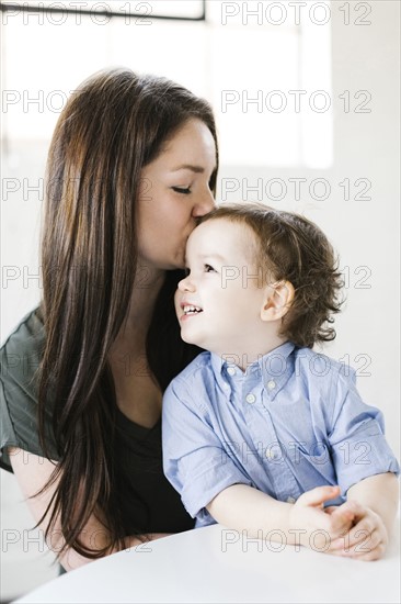 Mother giving son (4-5) forehead kiss