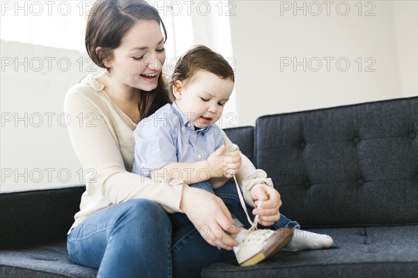 Mother tying son's (4-5) shoe