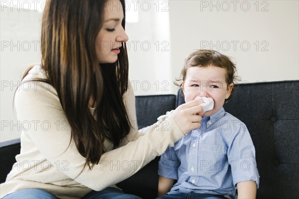 Mother helping son (4-5) blow nose