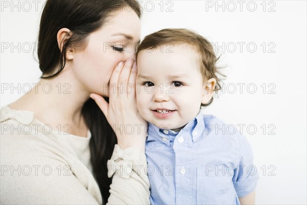 Mother whispering into son's (4-5) ear