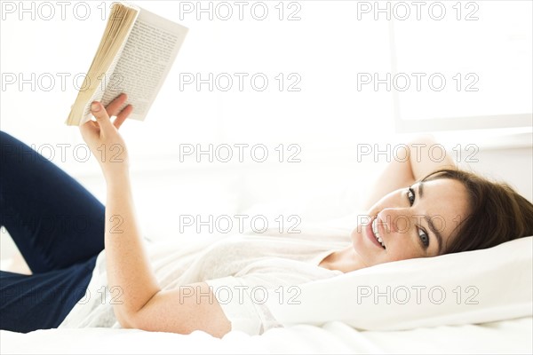 Woman reading book in bed