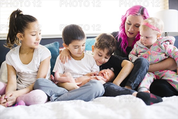 Children (2-3, 6-7, 8-9, 10-11) taking care of baby boy (2-5 months)