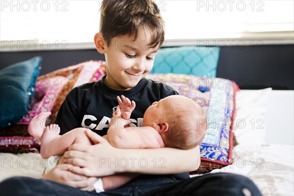 Young boy (6-7) holding brother (2-5 months)