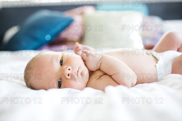 Baby boy (2-5 months) lying in bed