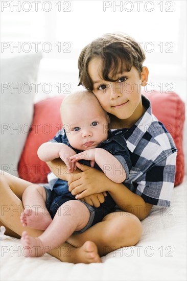 Young boy (6-7) holding brother (2-5 months)