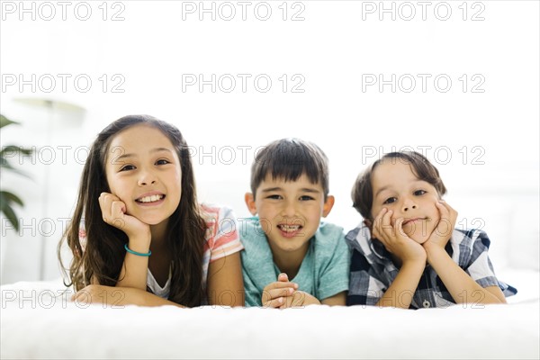 Siblings (10-11, 6-7, 8-9) lying in bed side by side