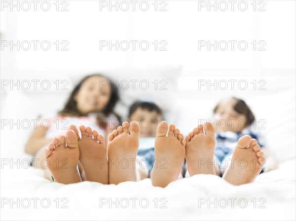 Siblings (10-11, 6-7, 8-9) lying in bed side by side