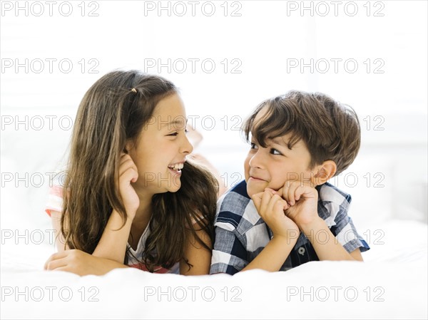 Siblings (10-11, 6-7) lying in bed side by side