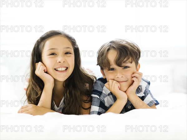 Siblings (10-11, 6-7) lying in bed side by side