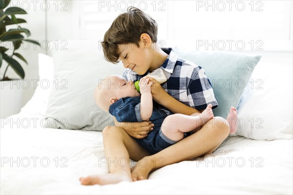 Young boy (6-7) feeding brother (2-5 months)