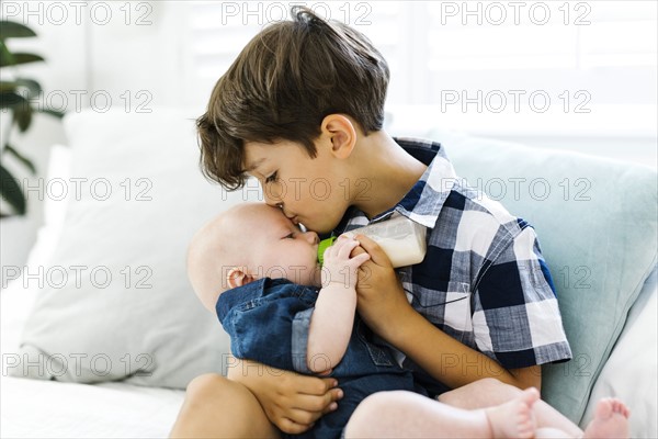 Boy( 6-7) feeding small brother (12-17 months)