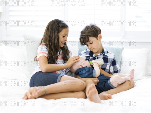 Siblings ( 6-7, 10-11, 12-17 months ) sitting on sofa