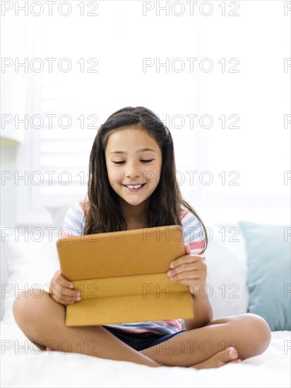 Smiling girl  (10-11) sitting and watching tablet