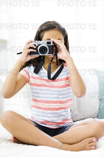 Sitting girl  (10-11) holding camera and taking photo