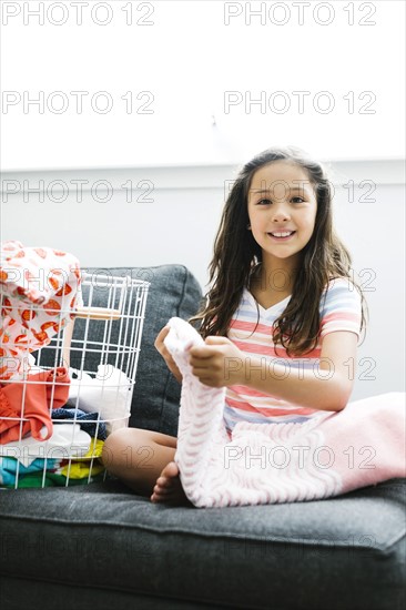 Girl (10-11 ) with laundry sitting on sofa