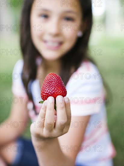 Girl (10-11) presenting strawberry