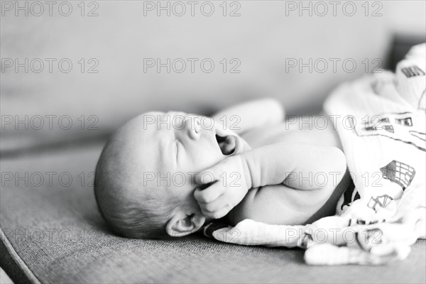 Baby boy (0-1 months) lying on back and yawning