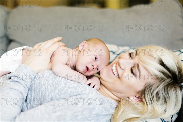 Mother lying on sofa and holding  his one day son (0-1 months)