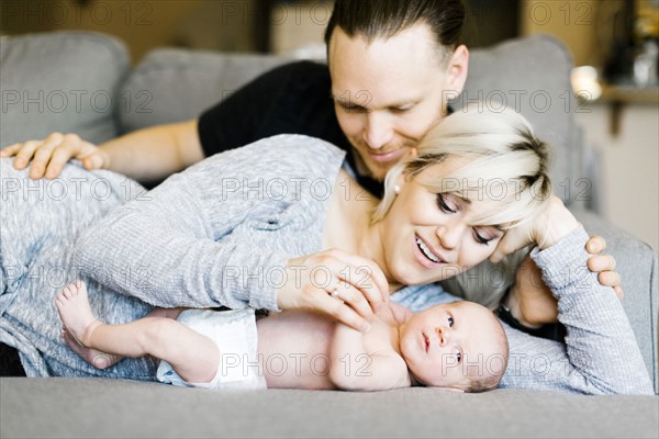 Family with one day son (0-1 months) lying on sofa