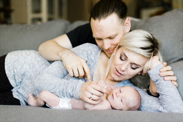 Family with one day son (0-1 months)  lying on sofa