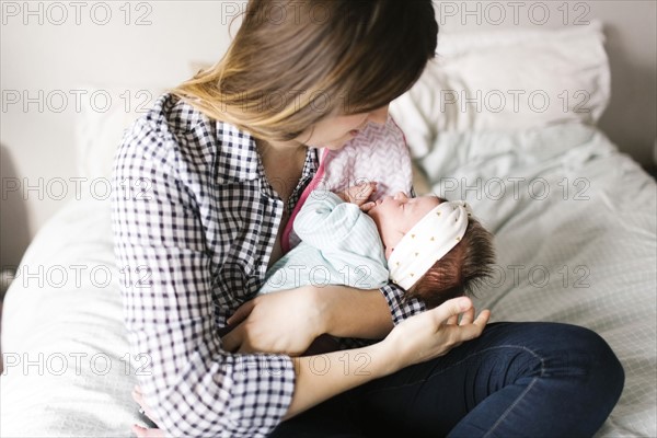 Young mother with baby girl (0-1 months) sitting in bedroom