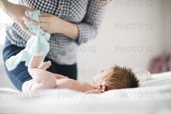 Young mother changing diaper to baby girl (0-1 months)