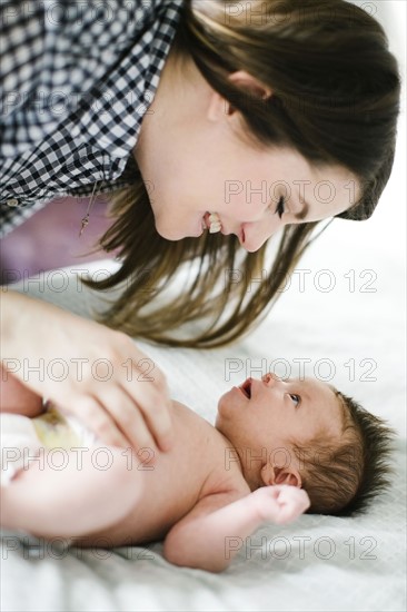 Young mother with baby girl (0-1 months) lying on bed