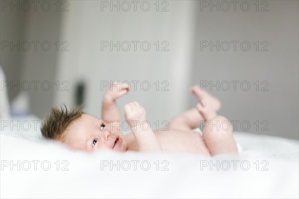 Naked baby girl (0-1 months) lying on bed