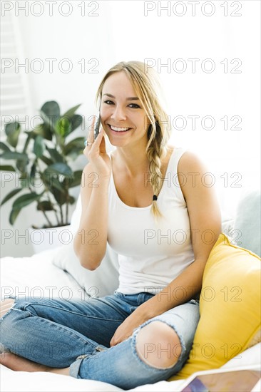 Young woman with mobile phone sitting on sofa