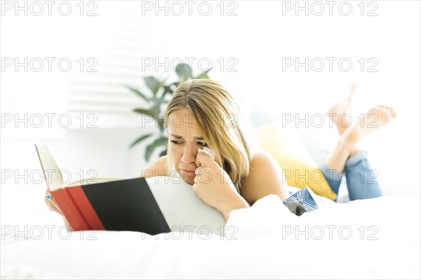 Young woman reading book and crying