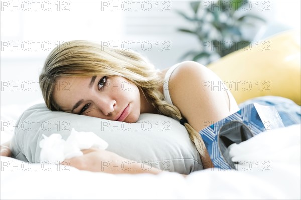 Sad young woman lying on bed and crying