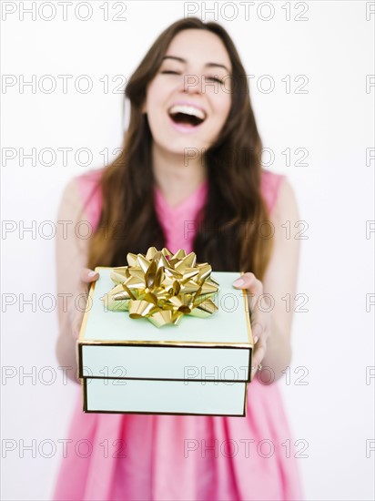 Mid adult woman holding gift box and laughing