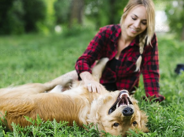 Young woman playing with golden retriever in park