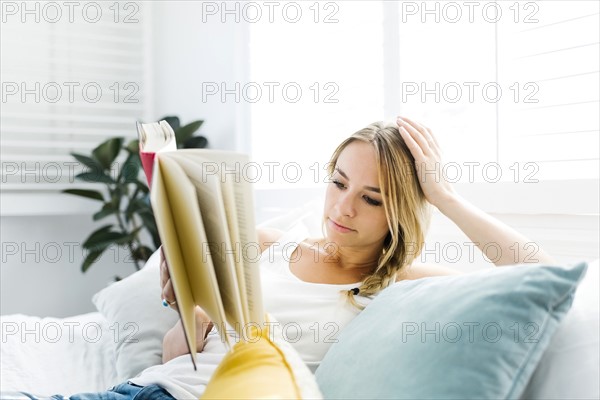 Woman reading book on sofa