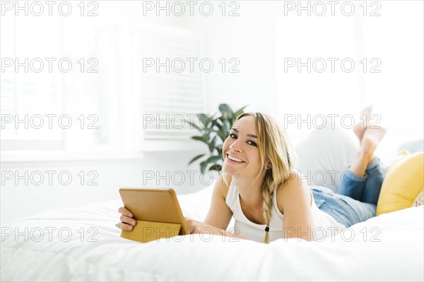 Woman with digital tablet lying on bed