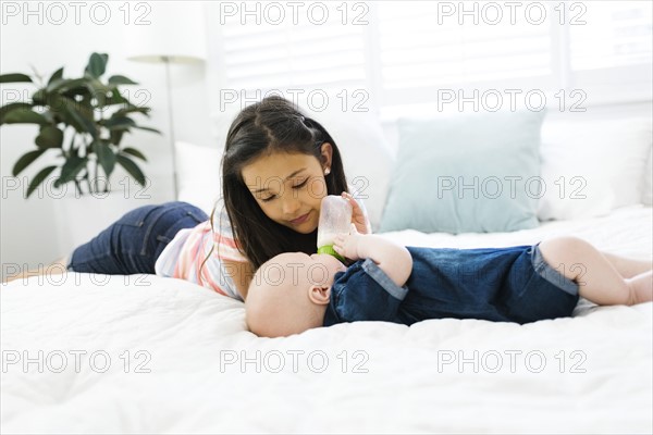 Sister ( 10-11 ) feeding brother ( 2-5 months ) with baby bottle