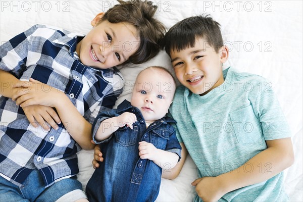 Portrait of brothers ( 2-5 months, 6-7, 8-9 ) lying on bed