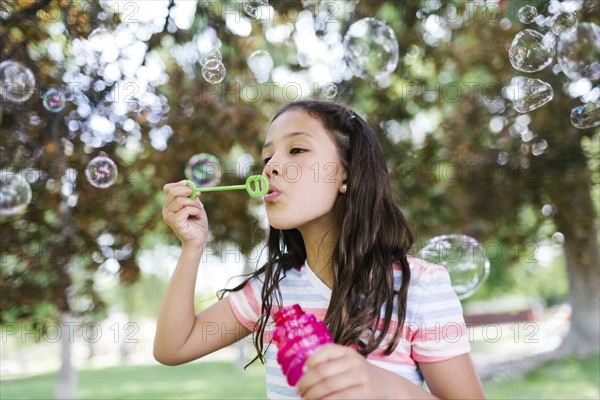 Portrait of girl ( 10-11 )  blowing soap bubbles