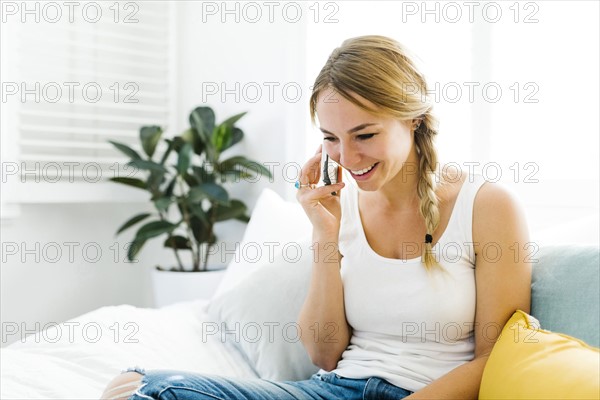 Young woman sitting on sofa and using smart phone