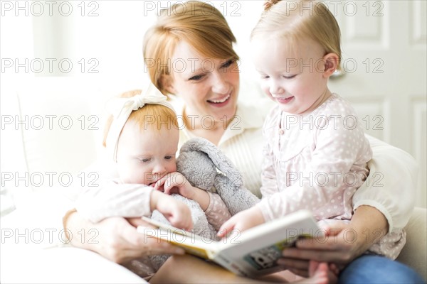 Mother reading book to daughters ( 12-17 months )