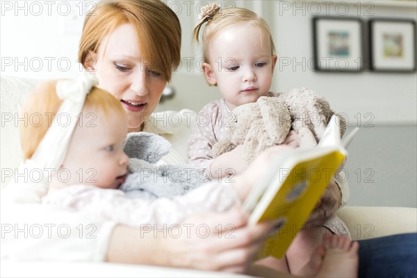 Mother reading book to daughters ( 12-17 months )
