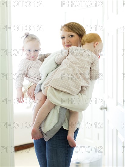 Portrait of mother embracing daughters ( 12-17 months )