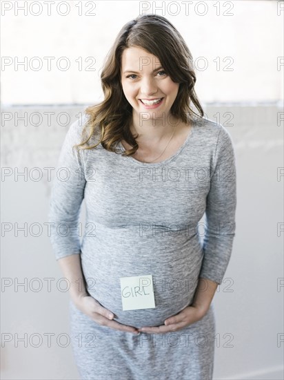 Portrait of smiling pregnant woman with adhesive note on belly